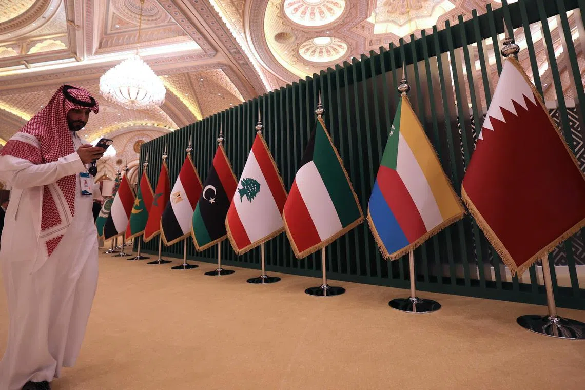 A Saudi man stands near national flags during the 10th Arab-China Business Conference in Riyadh, on June 11, 2023.