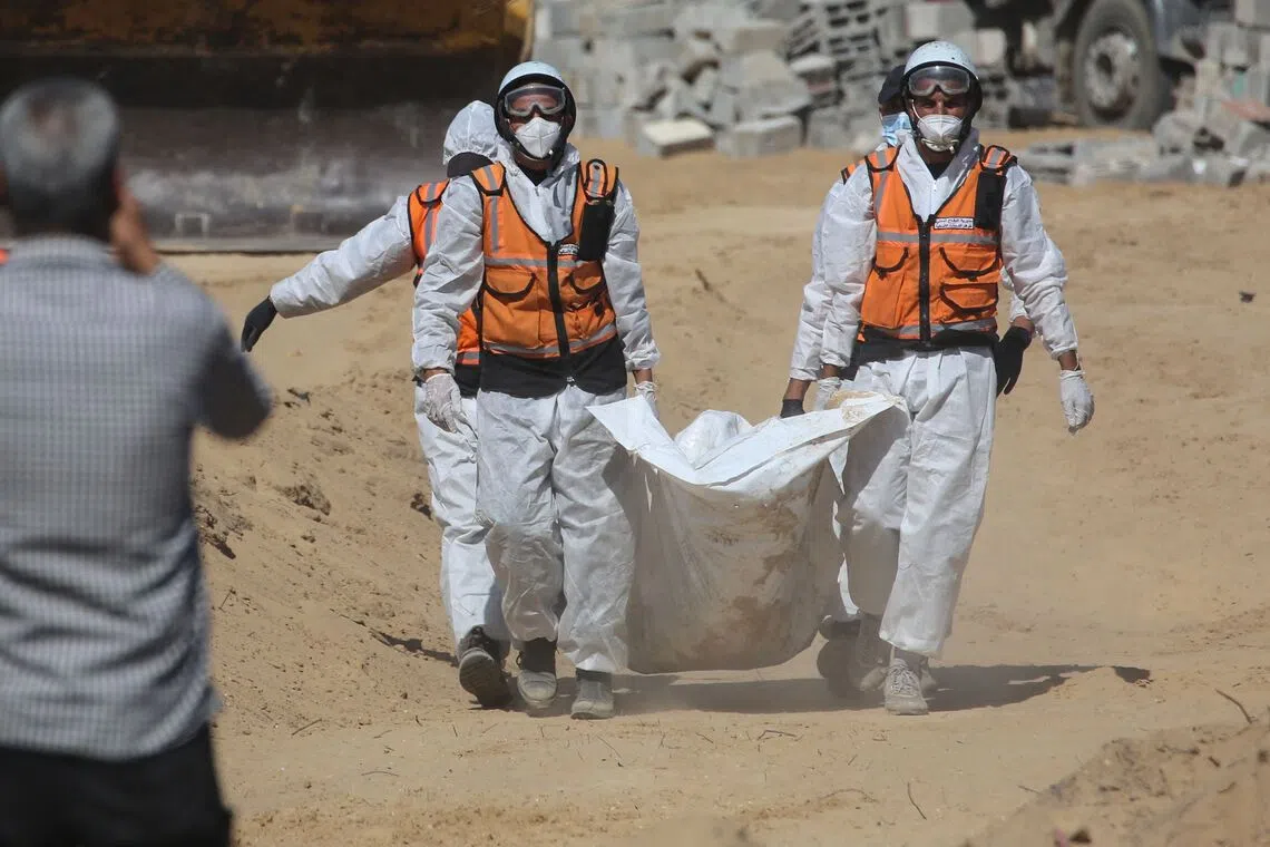Members of the Palestinian Civil Defence carry a body at a cemetery in Deir al-Balah after the remains of unidentified Palestinians were returned by Israel under a US-brokered ceasefire deal.