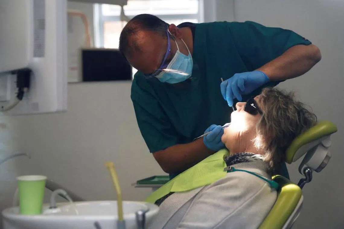 FILE PHOTO: A dentist tends to a patient at Silveroaks Dental Surgery as it opens for non aerosol generating assessments in Milton Keynes, following the outbreak of the coronavirus disease (COVID-19), Milton Keynes, Britain, June 8, 2020. REUTERS/Andrew Boyers