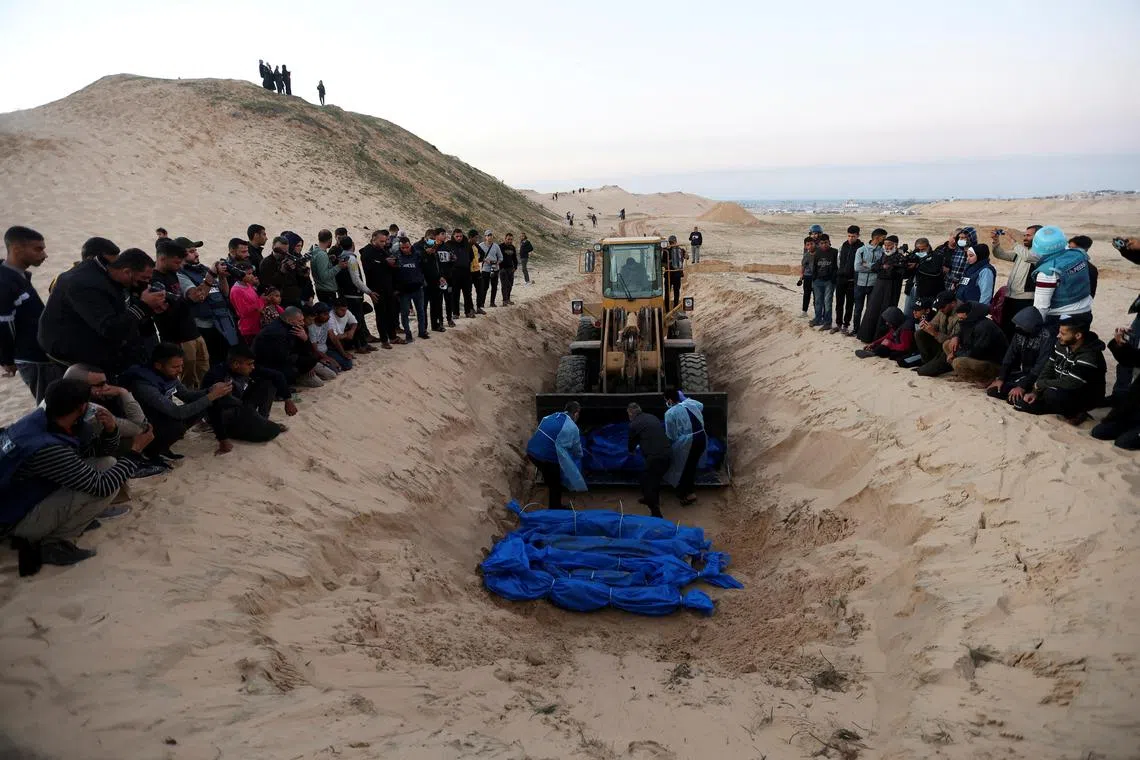 People bury Palestinians after their bodies were released by Israel, at a mass grave in Rafah, in the southern Gaza Strip.