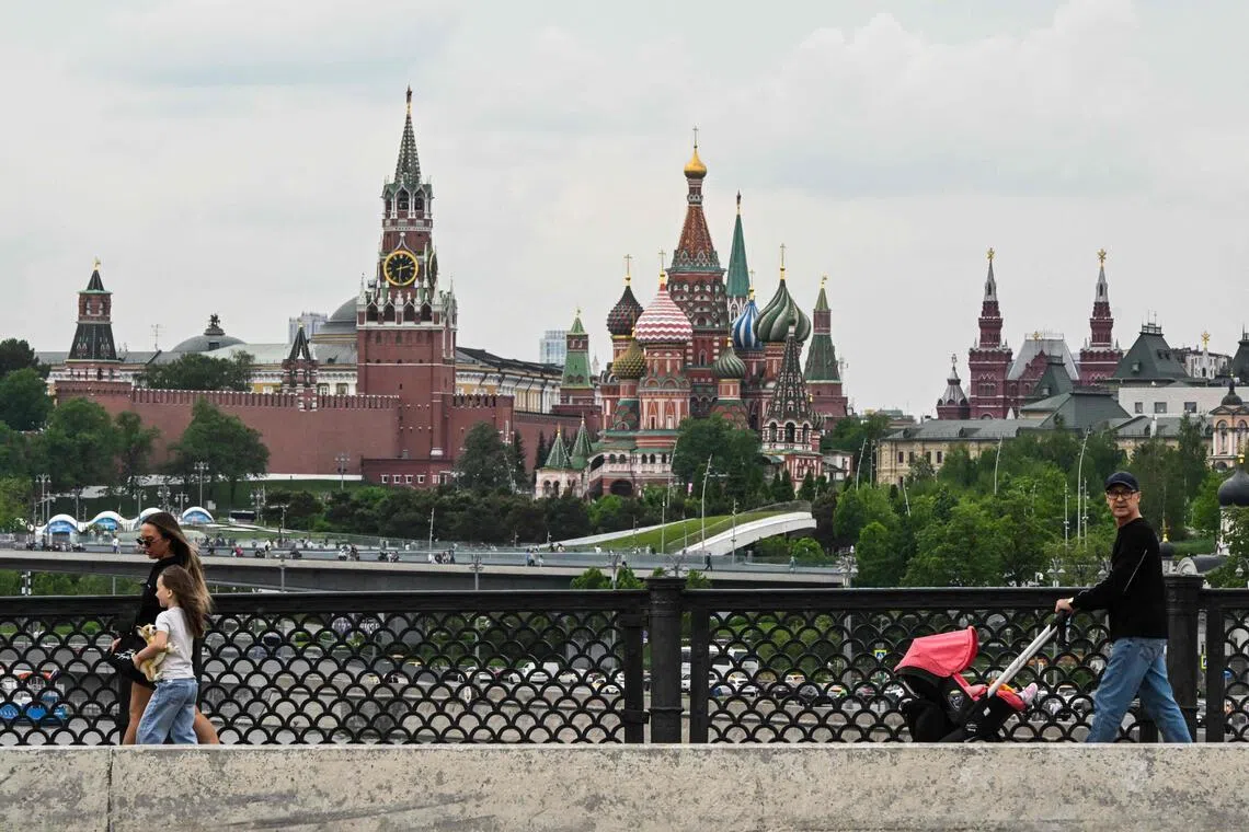 A family walks across Bolshoy Ustyinsky bridge, with Red Square in the background, in central Moscow on May 15, 2026. (Photo by Igor IVANKO / AFP)