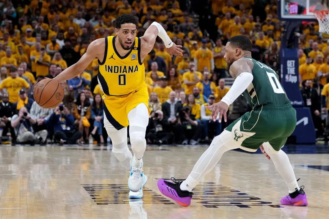 INDIANAPOLIS, INDIANA - APRIL 26: Tyrese Haliburton #0 of the Indiana Pacers dribbles the ball while being guarded by Damian Lillard #0 of the Milwaukee Bucks in overtime during game three of the Eastern Conference First Round Playoffs at Gainbridge Fieldhouse on April 26, 2024 in Indianapolis, Indiana. NOTE TO USER: User expressly acknowledges and agrees that, by downloading and or using this photograph, User is consenting to the terms and conditions of the Getty Images License Agreement.   Dylan Buell/Getty Images/AFP (Photo by Dylan Buell / GETTY IMAGES NORTH AMERICA / Getty Images via AFP)