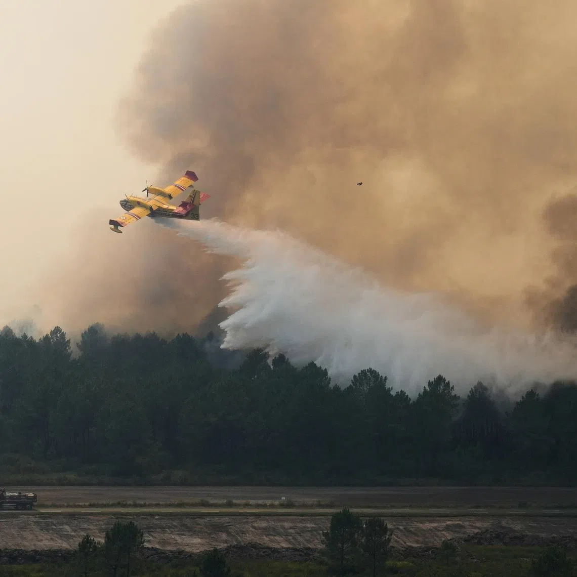 A plane drops water on a fire near Ares, during wildfires in the area of southwestern France, Tuesday, July 28, 2026. Baz Ratner/Pool via REUTERS