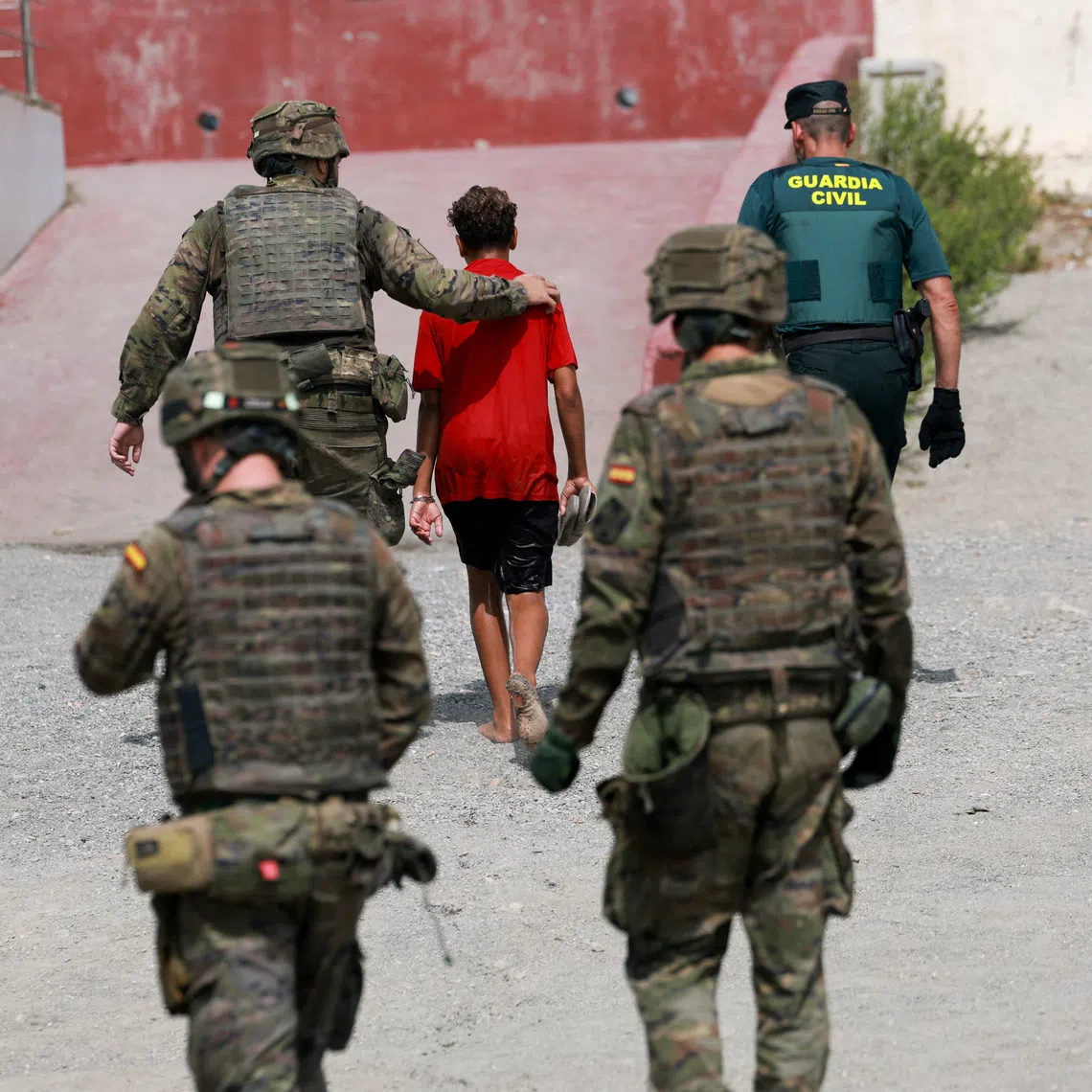 A migrant minor from Morocco is escorted by Spanish security forces after attempting to cross into Ceuta by sea amid recent mass crossings of migrants on foot and by sea from Morocco into Spanish territory, in Ceuta, Spain, August 1, 2026. REUTERS/Violeta Santos Moura
