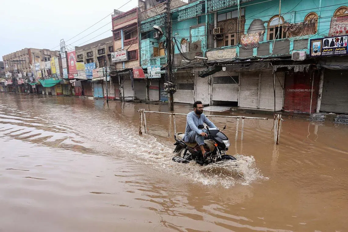 A motorcyclist riding his vehicle through floodwaters on a street after heavy monsoon rains in Multan, Pakistan, on Aug 28, 2024.