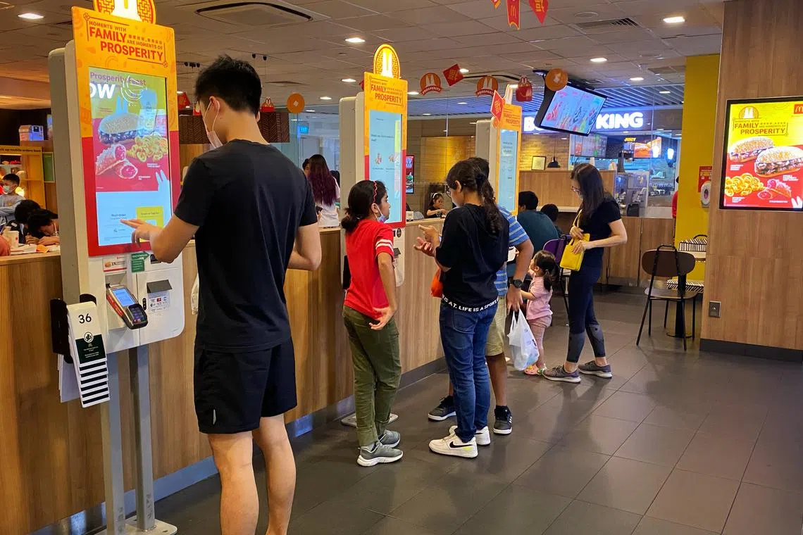 Slug: yhmacs02 ST PHOTO: Chong Jun Liang Customers ordering their food at McDonald’s at Compass One on January 2, 2023. Fast food restaurants McDonald's, KFC and Burger King charge different prices for the same items in different areas here, according to a check by The Straits Times in nine areas. This follows an online Reddit post that sparked discussion about price discrimination of Big Macs across outlets. Have asked all three chains to comment, and asked experts on the reasons for differentiated pricing.