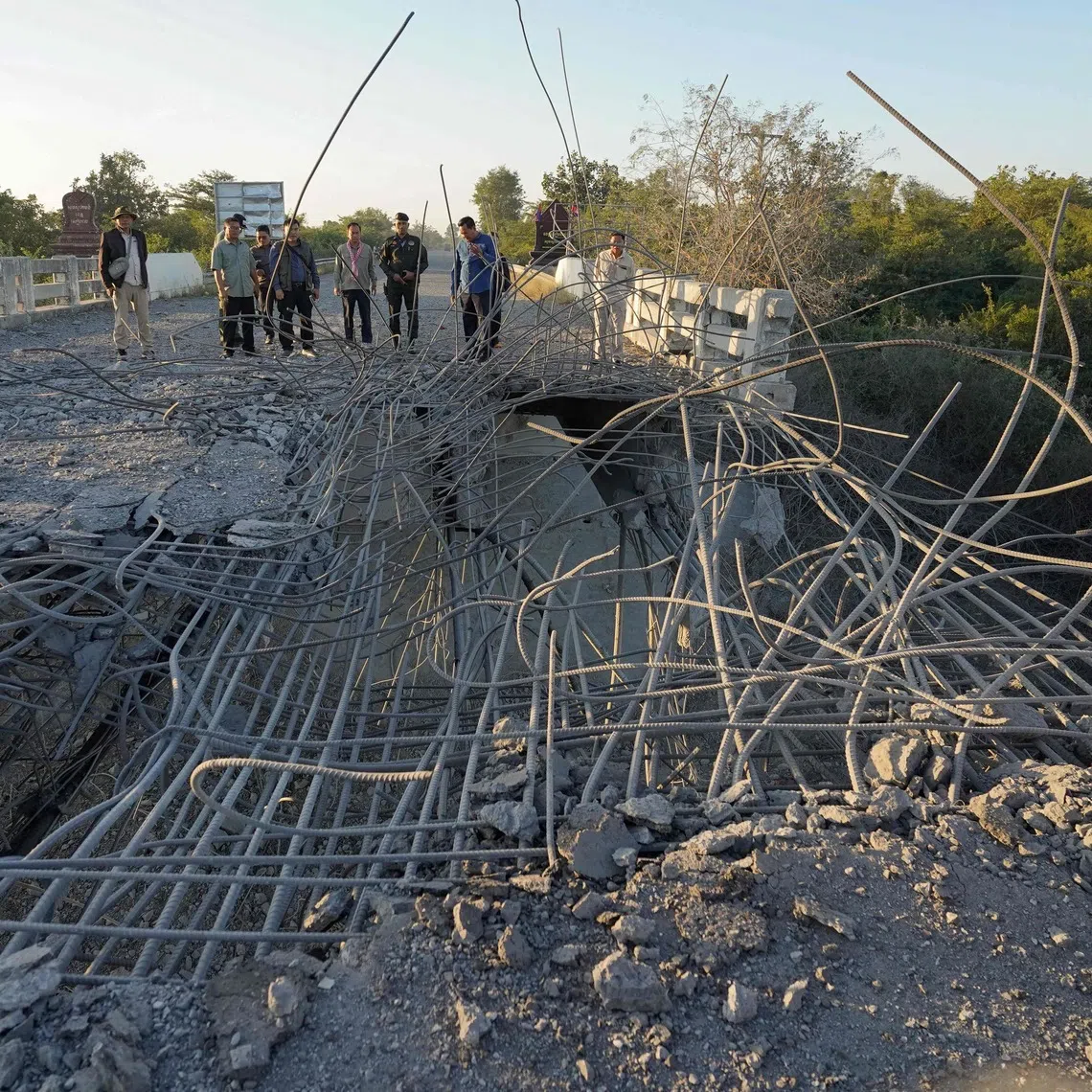People look at a damaged bridge after Thailand carried out air strikes in an area between Cambodia's Oddar Meanchey and Siem Reap provinces on Dec 20.