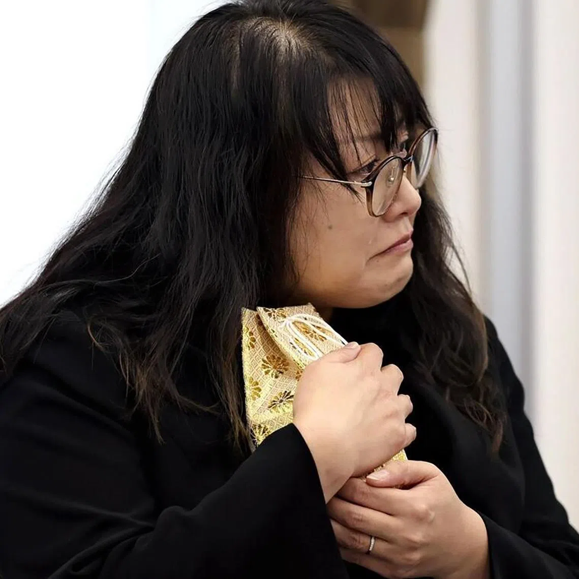 Ms Chiyumi Yamane cuddling the small urn containing the partial remains of her daughter Natsuse.