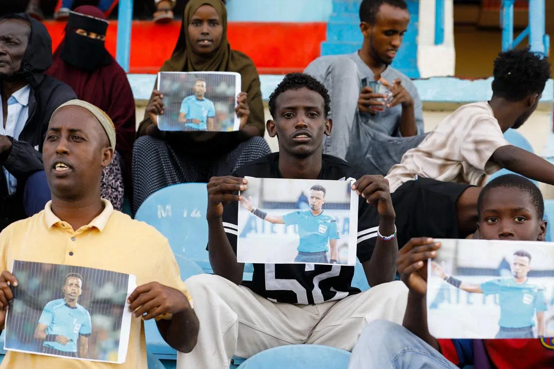 Somalis hold pictures of referee Omar Abdulkadir Artan, who had been expected to officiate matches at the 2026 FIFA World Cup but was refused entry to the United States, at a stadium in Somalia on June 9.