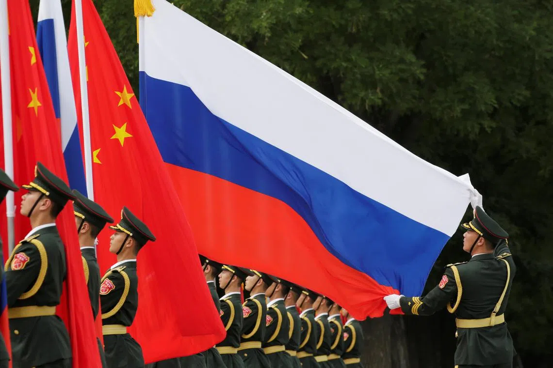 A military officer adjusts a Russian flag ahead of a welcome ceremony hosted by Chinese President Xi Jinping for Russian President Vladimir Putin outside the Great Hall of the People in Beijing, China June 8, 2018. REUTERS/Jason Lee/File Photo
