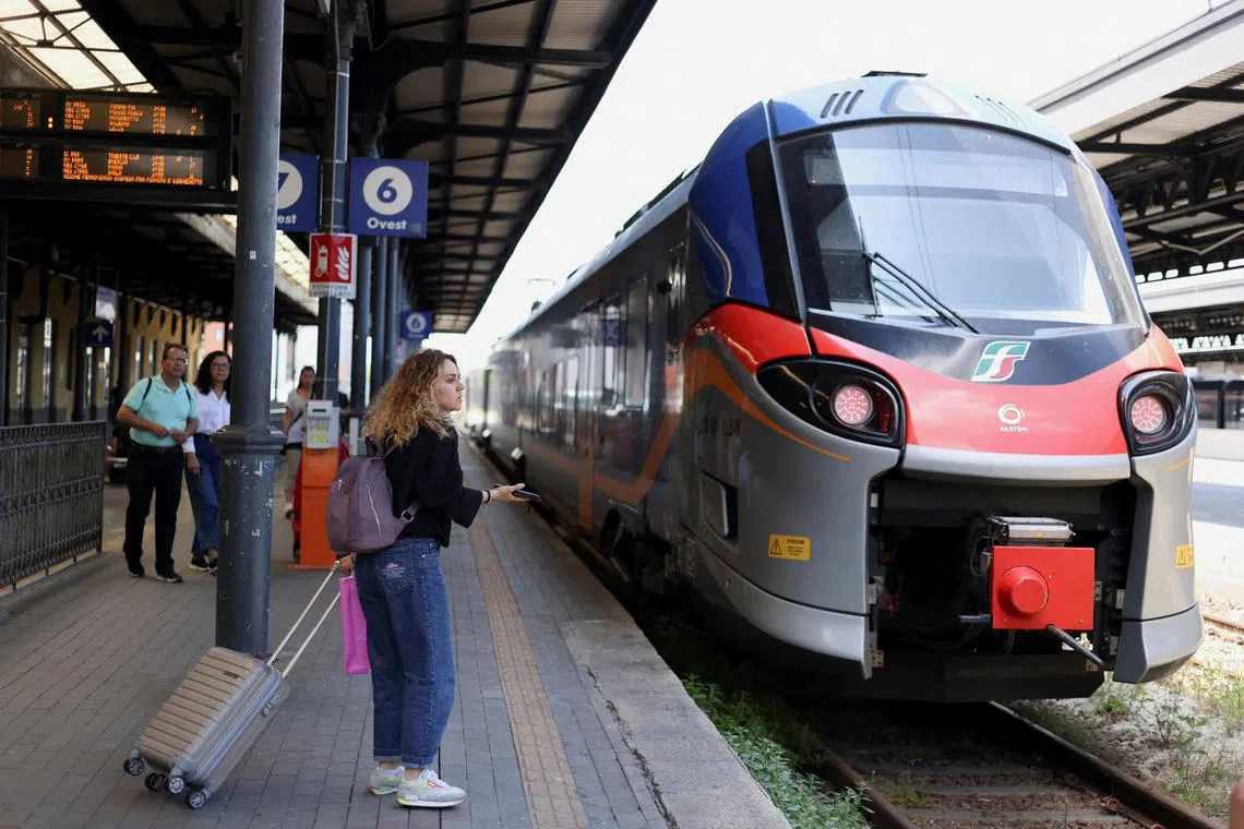 FILE PHOTO: A passenger waits before bording on a Trenitalia train at the central railway station in Bologna, Italy June 9, 2023. REUTERS/Claudia Greco/File Photo