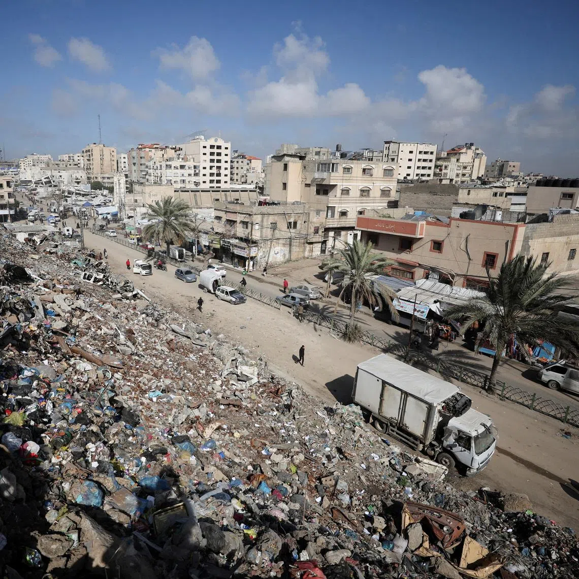 Palestinians walk near a landfill, in Gaza City, February 11, 2026. REUTERS/Dawoud Abu Alkas