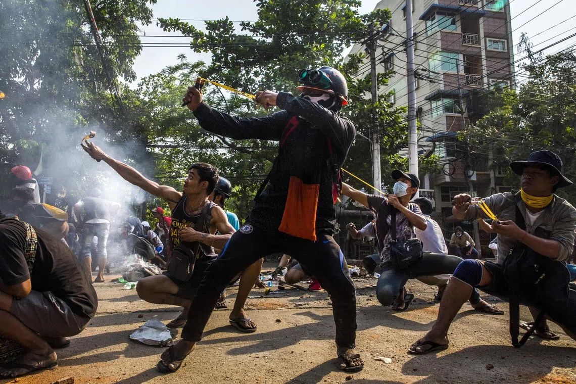 During a clash, protesters use homemade weapons such as airguns and slingshots to defend against security forces entering their neighborhood in Yangon, Myanmar, on March 28, 2021. 