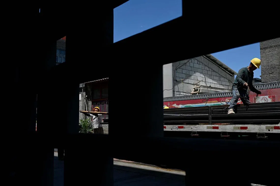 Two workers unloading materials from a truck at a construction site in Beijing on June 3, 2025. 