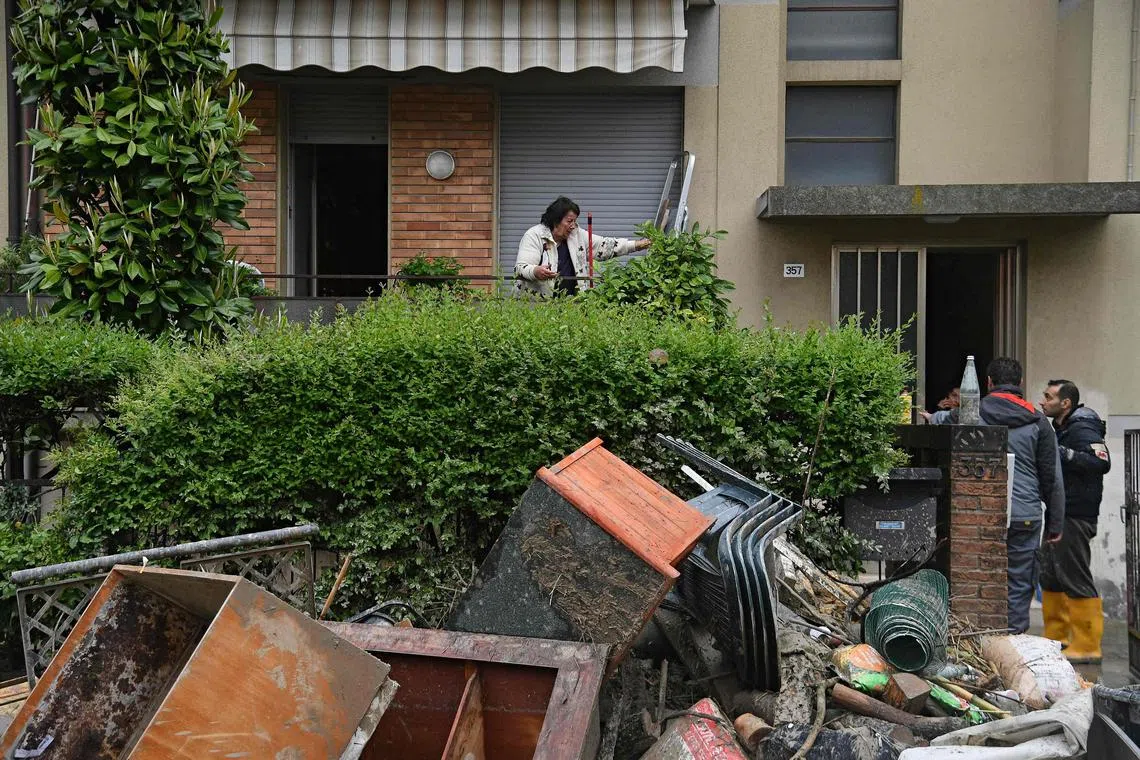 Local residents observe the aftermath of a flooding in a street of the San Rocco district of Cesena on May 17, 2023. 