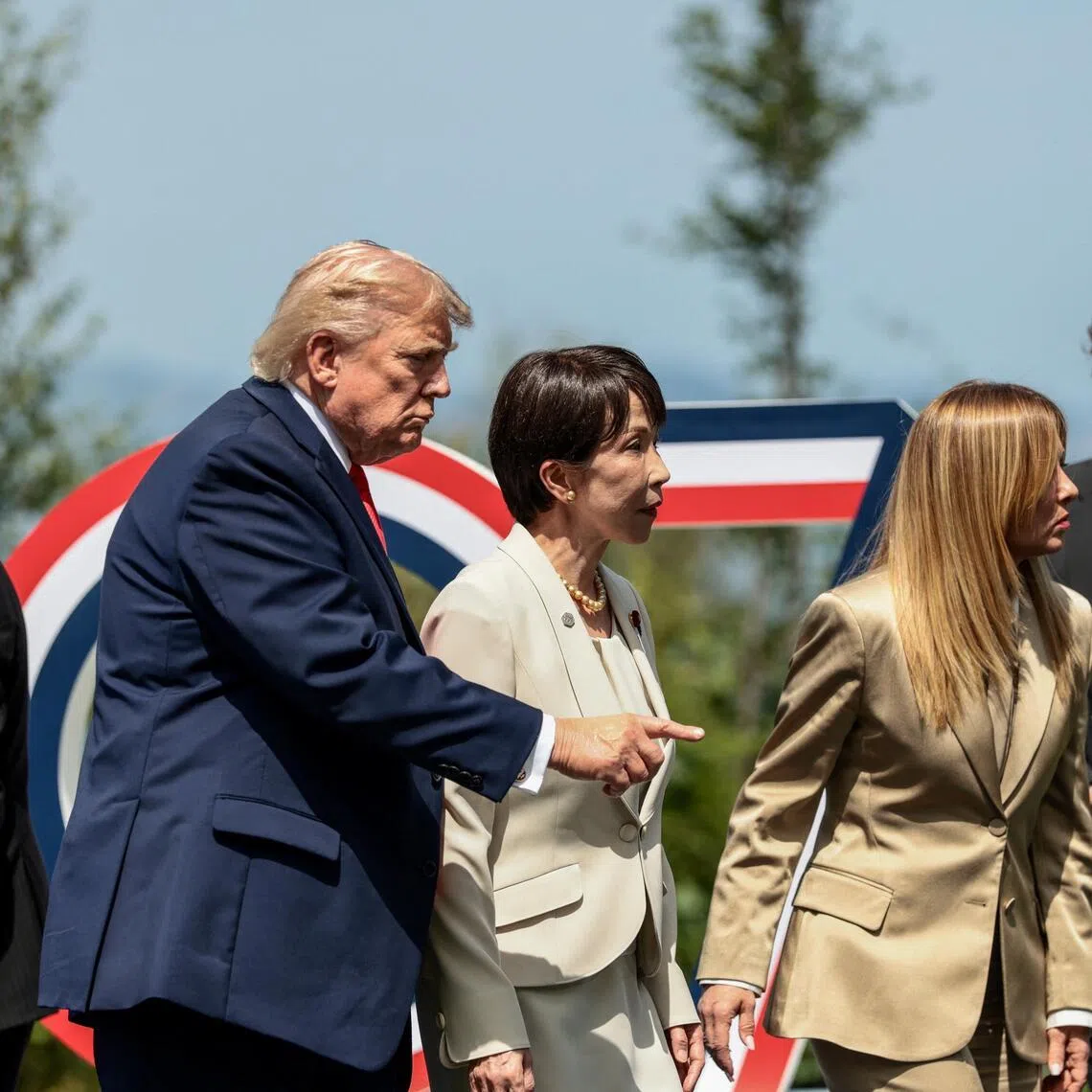 US President Donald Trump gestures next to Japanese Prime Minister Sanae Takaichi and Italian Prime Minister Giorgia Meloni following a group photo during the G-7 summit in Evian-les-Bains.