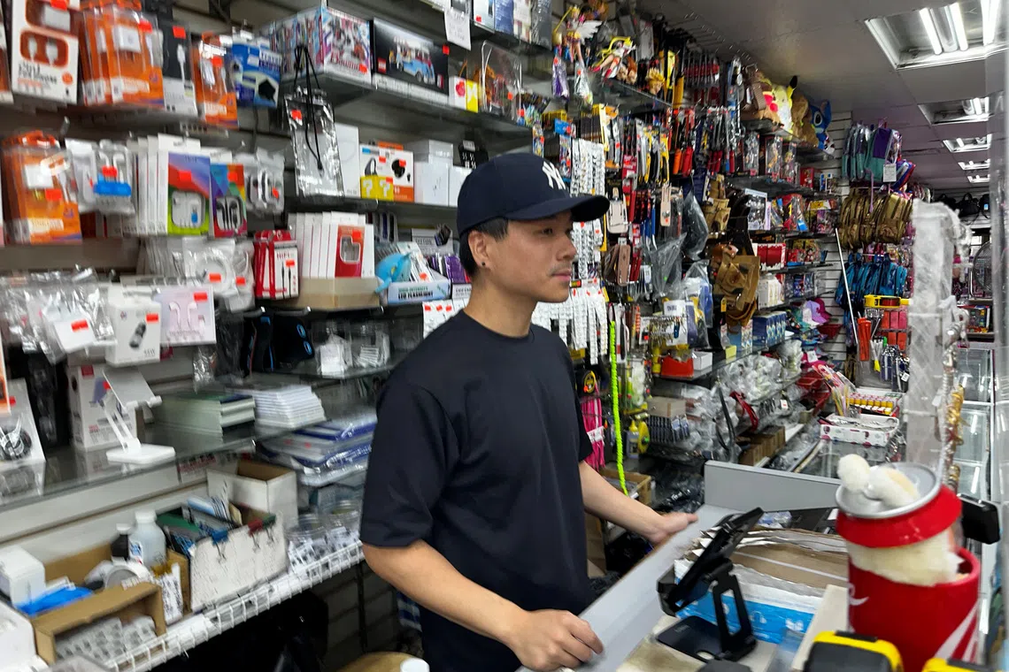 S. Shan works the cash register of his family's store, the Tien Rong Gift Shop, in the heavily Latino Ironbound section of Newark, N.J., U.S. September 16, 2025. REUTERS/Nicholas P. Brown