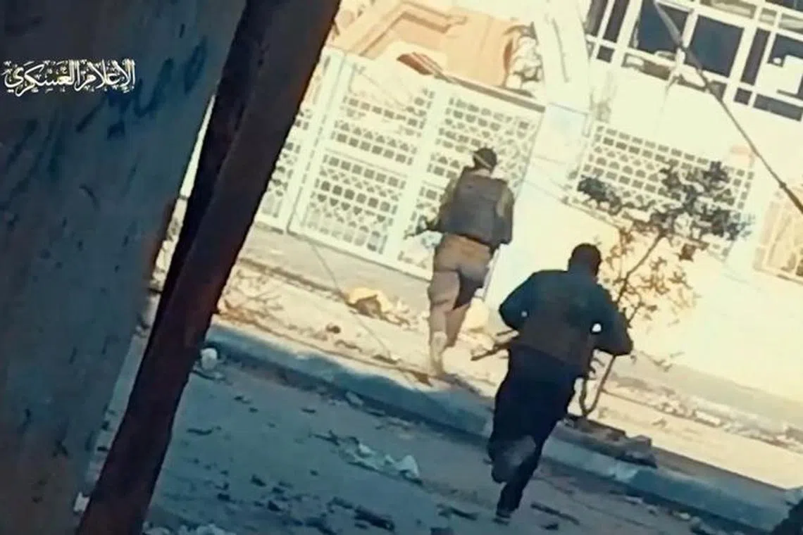 Hamas fighters run across the street at Rantissi hospital, amid the ongoing conflict between Israel and the Palestinian Islamist group Hamas, in Gaza City, in this screen grab taken from a handout video released on November 19, 2023. Hamas Military Wing/Handout via REUTERS/File Photo