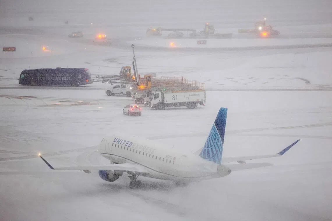 An Embraer 175 of United airlines taxies to take off as the snow falls on the tarmac of LaGuardia airport in New York on Jan 25, 2026. 