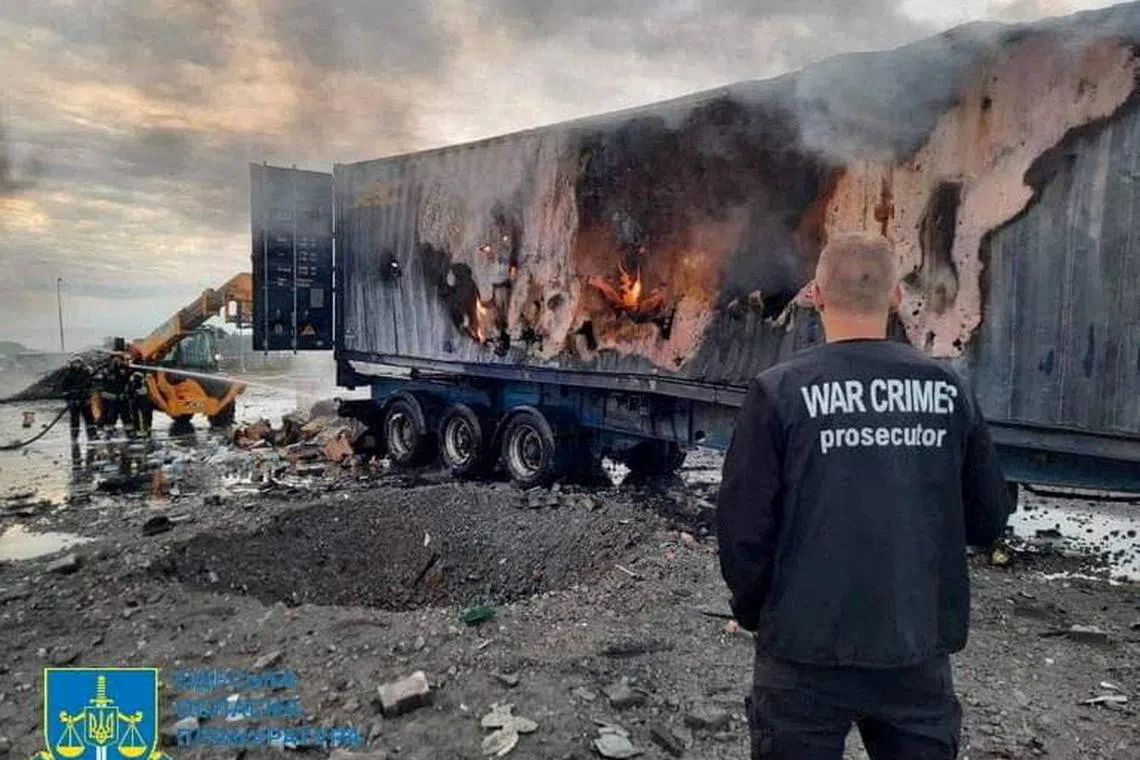 A war crimes prosecutor stands next to a crater and a truck damaged by a Russian strike at a Ukrainian port on Danube river.