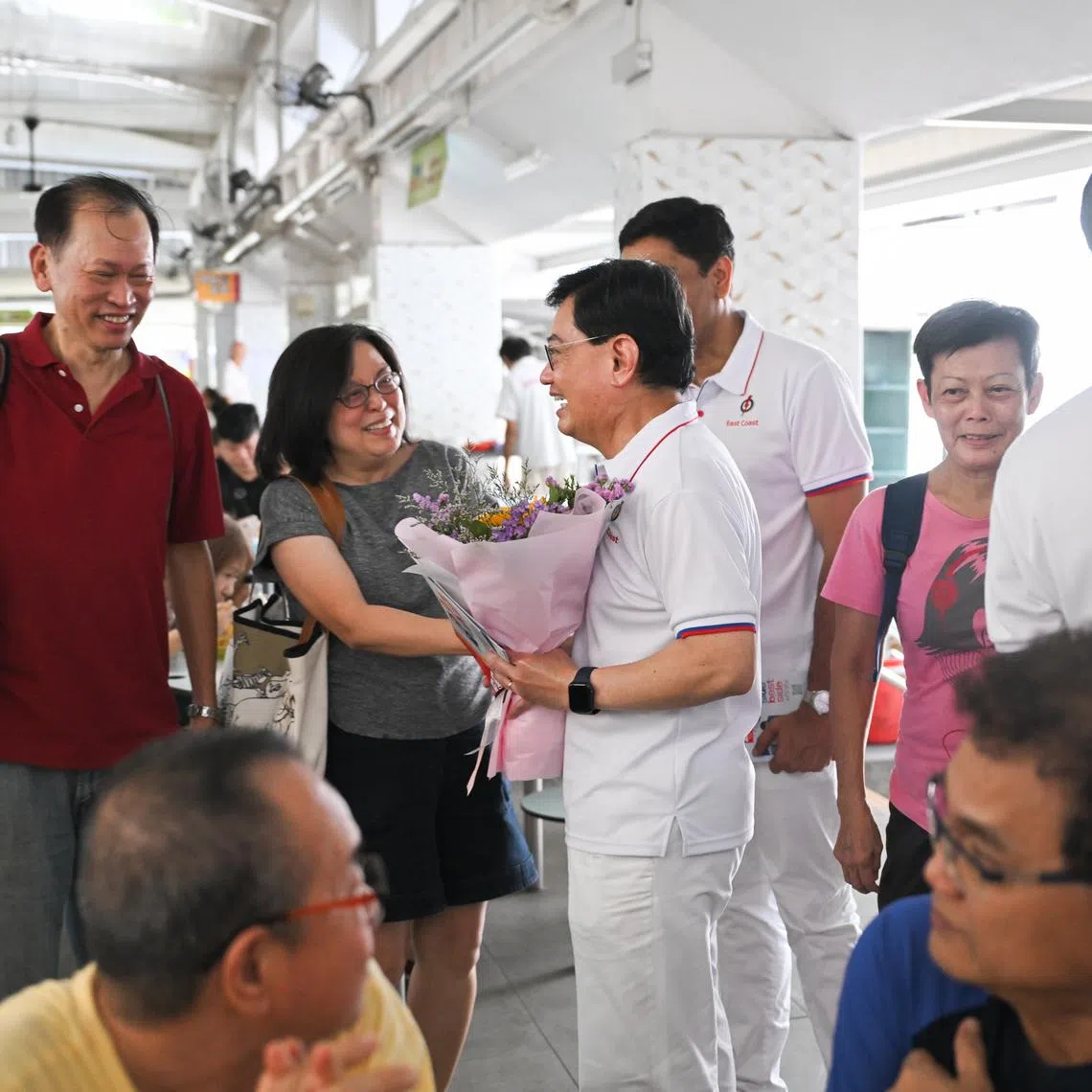 DPM Heng Swee Keat receiving a bouquet of flowers from residents at a walkabout at Block 216 Bedok Food Centre on May 1.