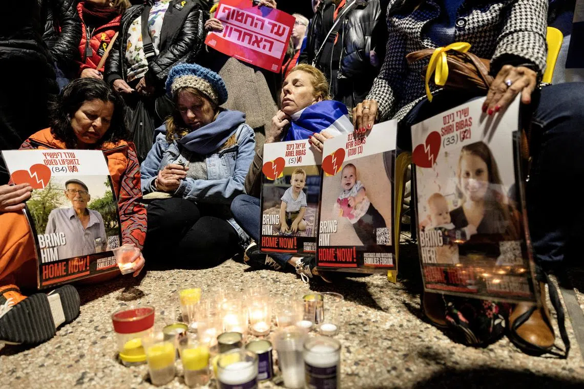 Israelis sit together as they light candles and hold posters with the images Oded Lifschitz, Shiri Bibas and her two children, Kfir and Ariel Bibas, seized during the deadly October 7, 2023 attack by Hamas, on the day the bodies of deceased hostages, identified at the time by Palestinian militant groups as Lifschitz, Shiri Bibas and her two children, were handed over under the terms of a ceasefire between Hamas and Israel, in Tel Aviv, Israel February 20, 2025. REUTERS/Itay Cohen