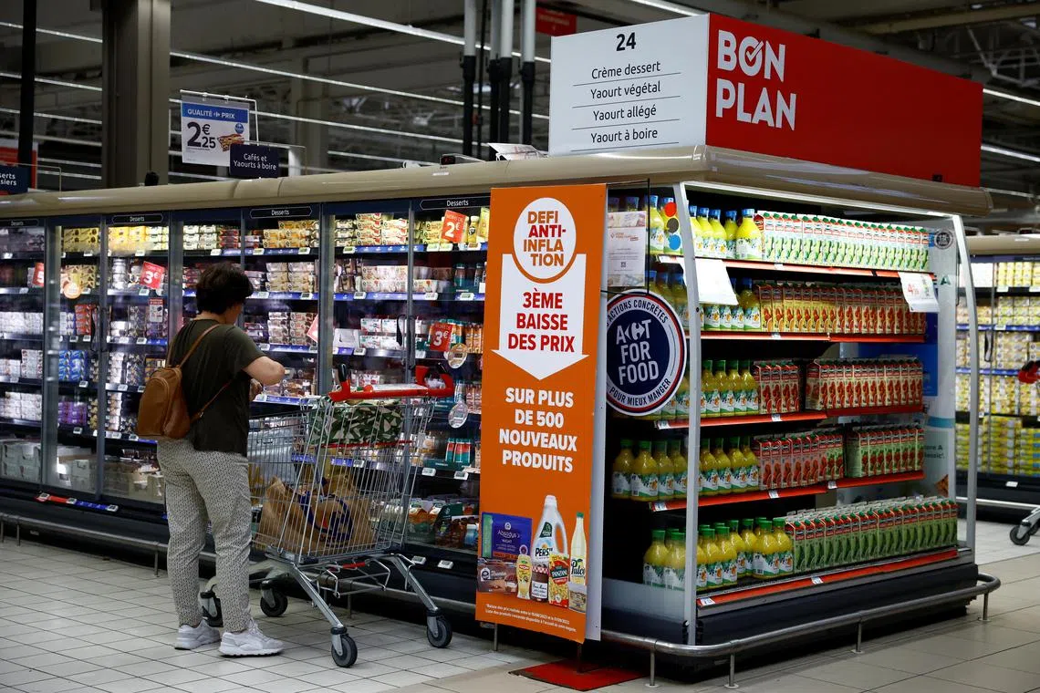 A sign reading "Anti-inflation challenge, third price cut" as a customer shops at a Carrefour supermarket in Montesson near Paris.