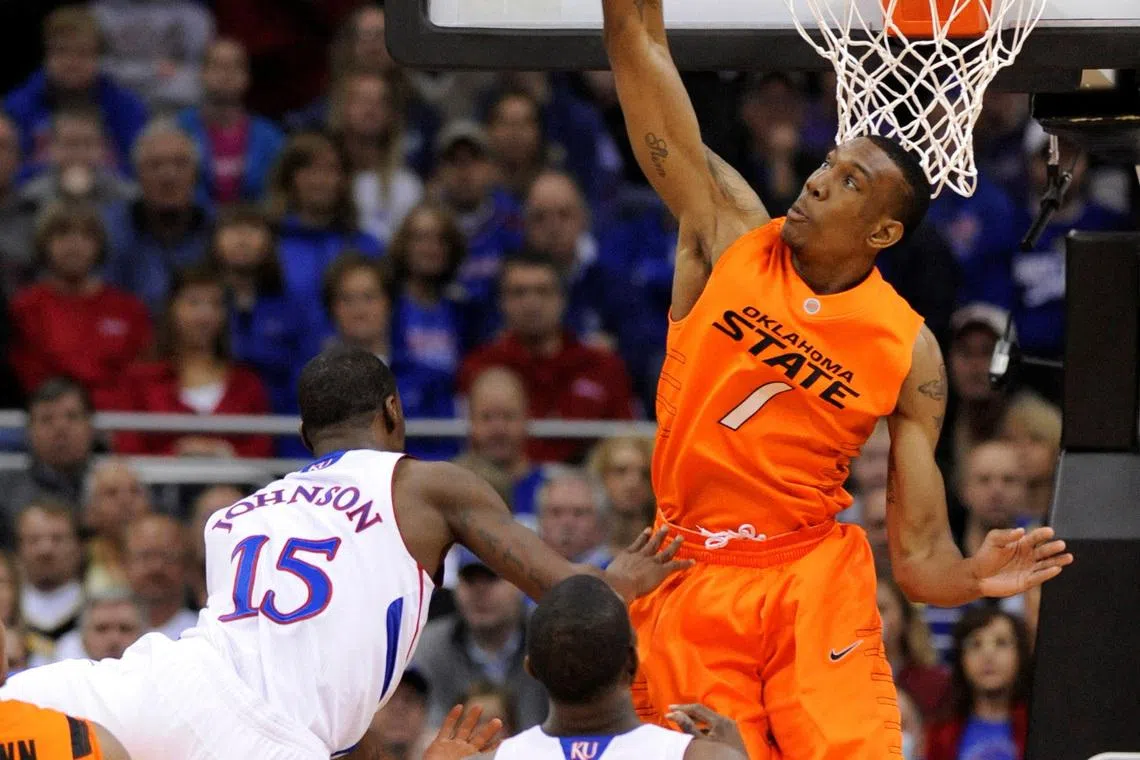 FILE PHOTO: Oklahoma State Cowboys forward Jarred Shaw rejects a shot by Kansas Jayhawk guard Elijah Johnson (L) during the first half of the quarter-finals of the NCAA men's Big 12 basketball championship at the Sprint Center in Kansas City, Missouri, March 10, 2011. REUTER/Dave Kaup/File Photo