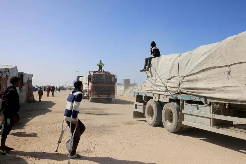 Palestinians look on as trucks carrying humanitarian aid arrive in Khan Younis in the southern Gaza Strip, after passing through the Rafah border crossing from Egypt, on Feb 1.