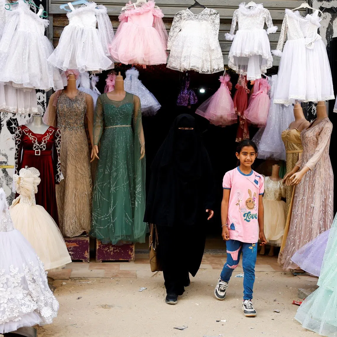 A Palestinian woman and a girl walk out of a wedding dress shop, as brides in Gaza turn to reused gowns amid soaring prices and shortages caused by the war, in Khan Younis in the southern Gaza Strip.