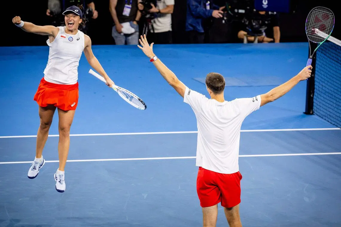 Poland's Iga Swiatek (L) and Hubert Hurkacz (R) celebrate their mixed doubles victory against Italy during the United Cup tennis tournament at the Patrick Rafter Tennis Centre in Brisbane on January 4, 2023. (Photo by Patrick HAMILTON / AFP) / -- IMAGE RESTRICTED TO EDITORIAL USE - STRICTLY NO COMMERCIAL USE --