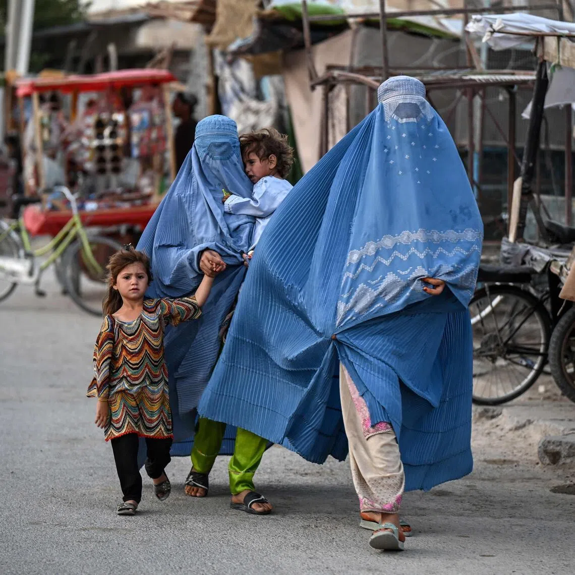 Afghan women clad in burqas, along with their children, walk along a road in Spin Ziyarat village in the Dand district of Kandahar on June 16. The vast majority of Afghan women do not work at all – less than 7 per cent of Afghan women were employed as of 2024, according to the UN Development Program.