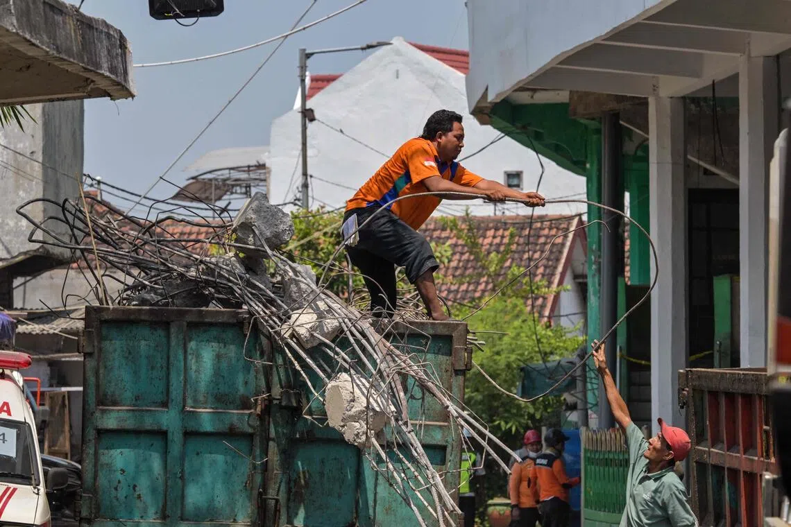Rescue teams move debris from the collapsed building onto trucks as search and rescue operations continue at the site of a collapsed school in Sidoarjo, East Java province.