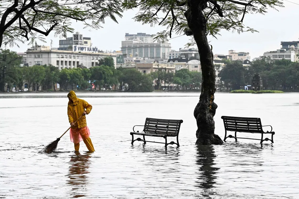 A worker sweeping the flooded edge of the Hoan Kiem Lake, after heavy rain caused by Tropical Storm Matmo in Hanoi, on Oct 7, 2025. 