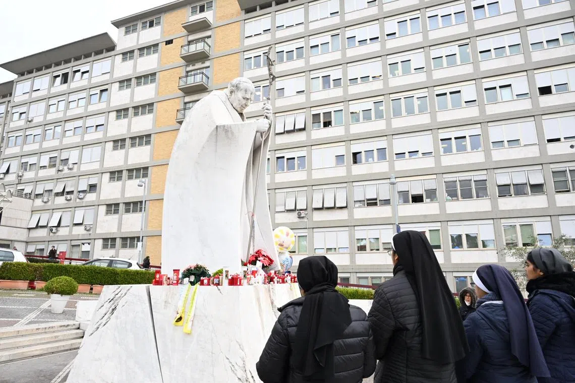 Nuns pray before the statue of late Pope John Paul II outside the Agostino Gemelli Hospital, where Pope Francis is hospitalised, on Feb 24.