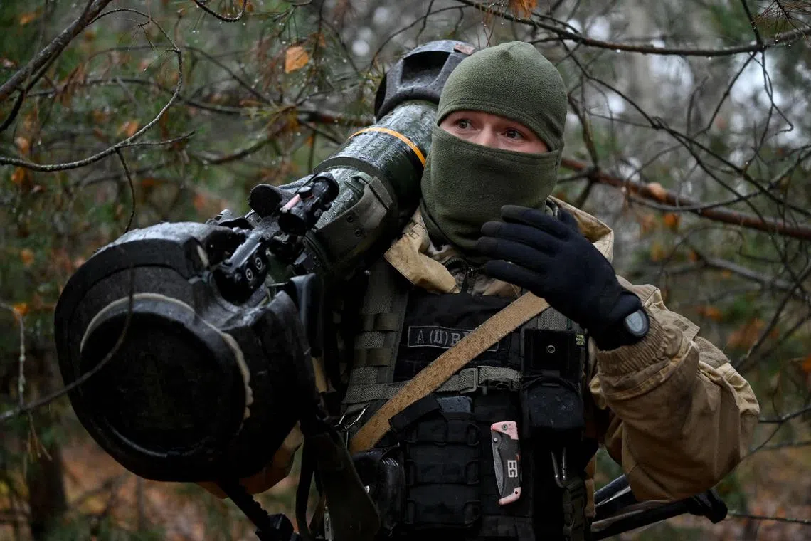 A Ukrainian border guard carries an Anglo-Swedish NLAW anti-tank missile launcher at a fortified position near the Ukrainian border with Russia and Belarus.