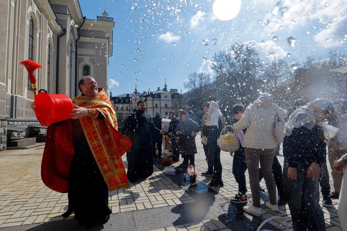 A priest sprays holy water on parishioners outside a cathedral during Orthodox Easter celebrations amid the Russia-Ukraine conflict in Donetsk, a Russian-controlled city of Ukraine, April 12, 2026. REUTERS/Alexander Ermochenko