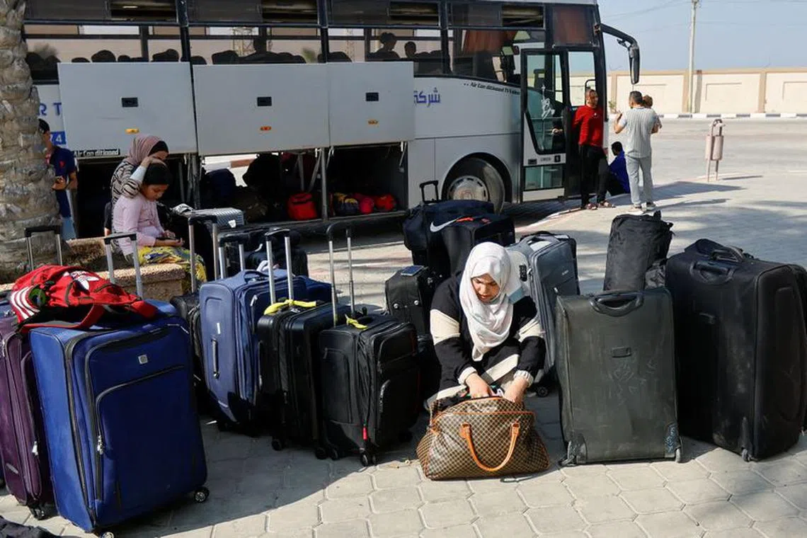 FILE PHOTO: A Palestinian holding a foreign passport looks through her bag as she waits for permission to leave Gaza, amid the ongoing conflict between Israel and Palestinian Islamist group Hamas, at the Rafah border crossing with Egypt, in Rafah in the southern Gaza Strip, November 3, 2023. REUTERS/Ibraheem Abu Mustafa/File Photo