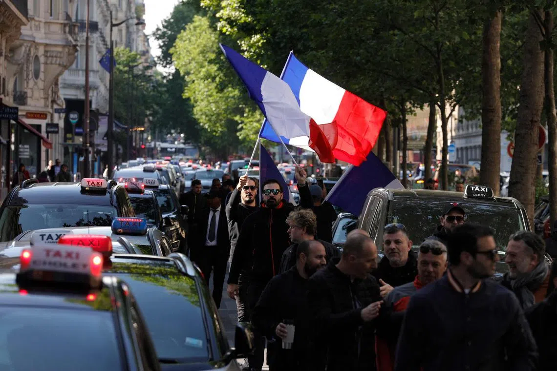 Taxis drivers wave French flag during a rally in a street in Paris on May 19, 2025.