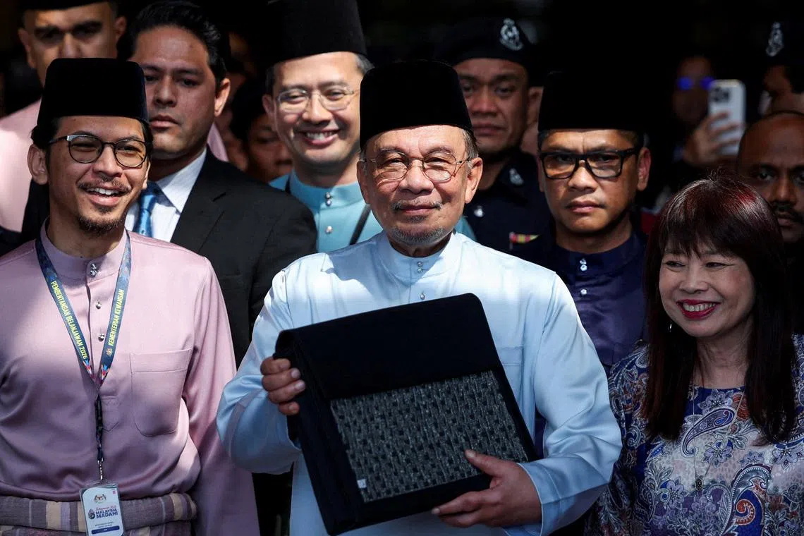 FILE PHOTO: Malaysia's Prime Minister and Finance Minister, Anwar Ibrahim, holds the 2026 national budget document at the Finance Ministry building as he departs for Parliament to table the budget, in Putrajaya, Malaysia, October 10, 2025. REUTERS/Hasnoor Hussain/File Photo