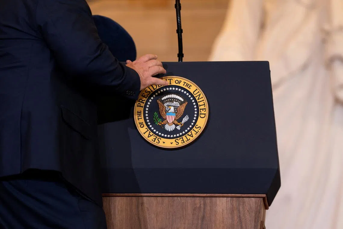 An aide places the Presidential seal before President Donald Trump addresses guests and supporters in an overflow room in Emancipation Hall of the U.S. Capitol for his Inauguration ceremony in Washington, D.C., on Monday, January 20, 2025.  Greg Nash/Pool via REUTERS