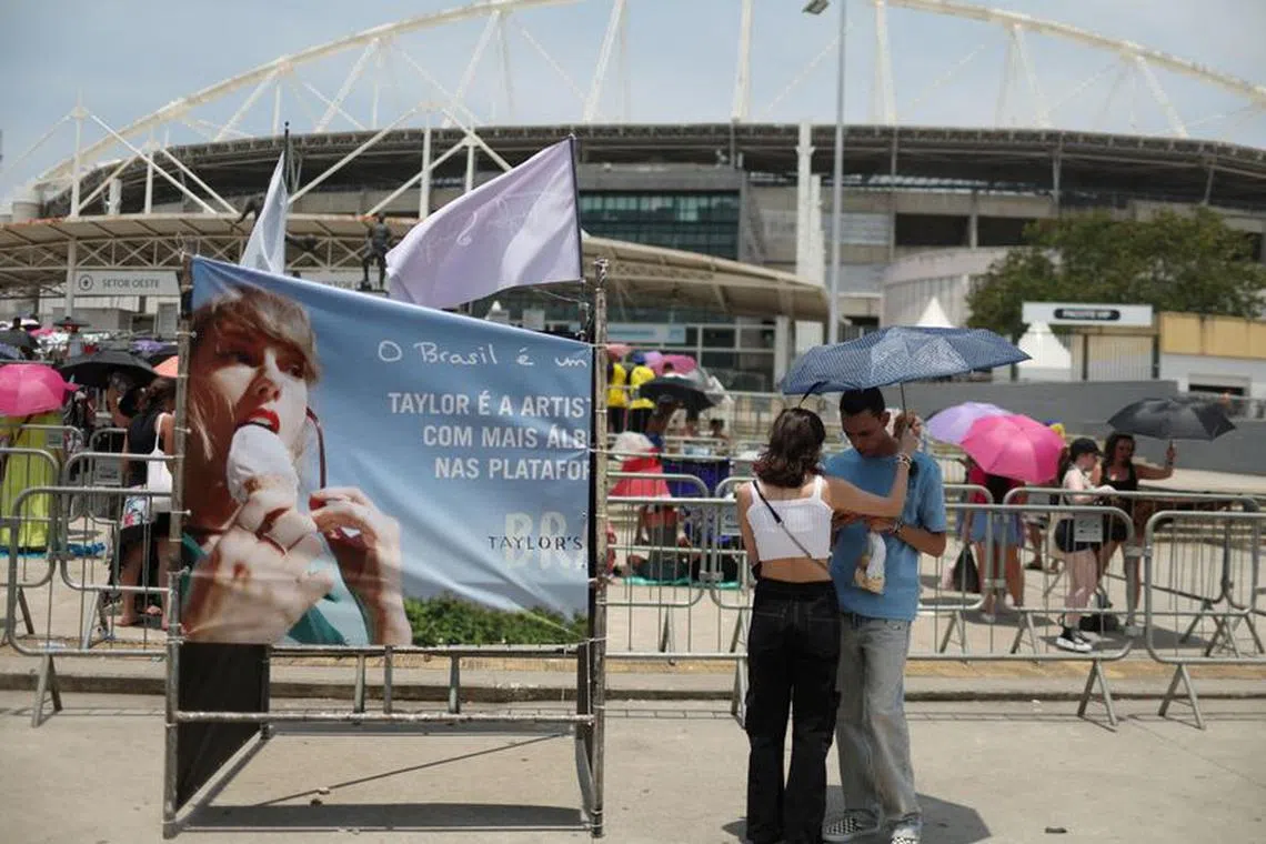 FILE PHOTO: A couple protect themselves with an umbrella for high temperatures, as they wait before the Taylor Swift concert, following the death of a fan due to the heat during the first day concert, in Rio de Janeiro, Brazil, November 18, 2023. REUTERS/Pilar Olivares/File Photo