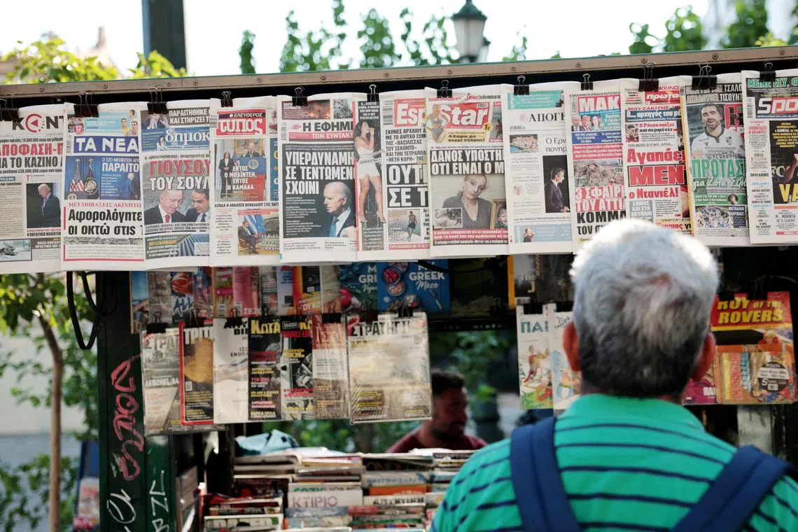 FILE PHOTO: A man looks at newspaper headlines at a kiosk, a day after U.S. President Joe Biden announced that he is dropping his reelection bid, in Athens, Greece, July 22, 2024. REUTERS/Louiza Vradi/File Photo