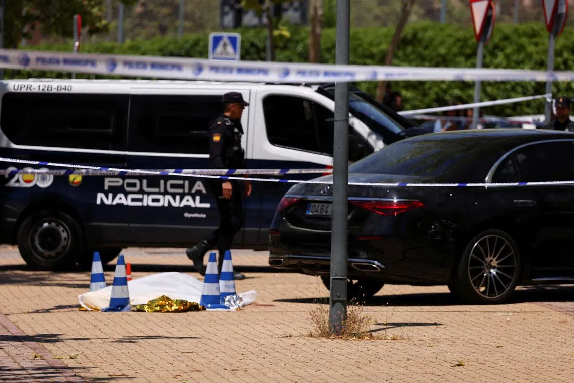 A Police officer walks near the body of former Ukrainian politician Andriy Portnov, at the spot where, according to the Spain's Interior Ministry, he was shot and killed by unidentified gunmen, outside a school, in Madrid, Spain May 21, 2025. REUTERS/Nacho Doce