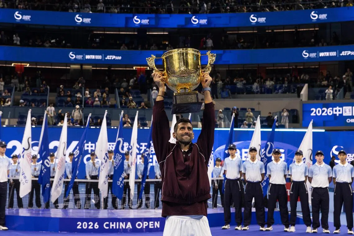 Novak Djokovic celebrating with the trophy after winning the China Open on Oct 6, following the retirement of Australia’s Alex de Minaur.