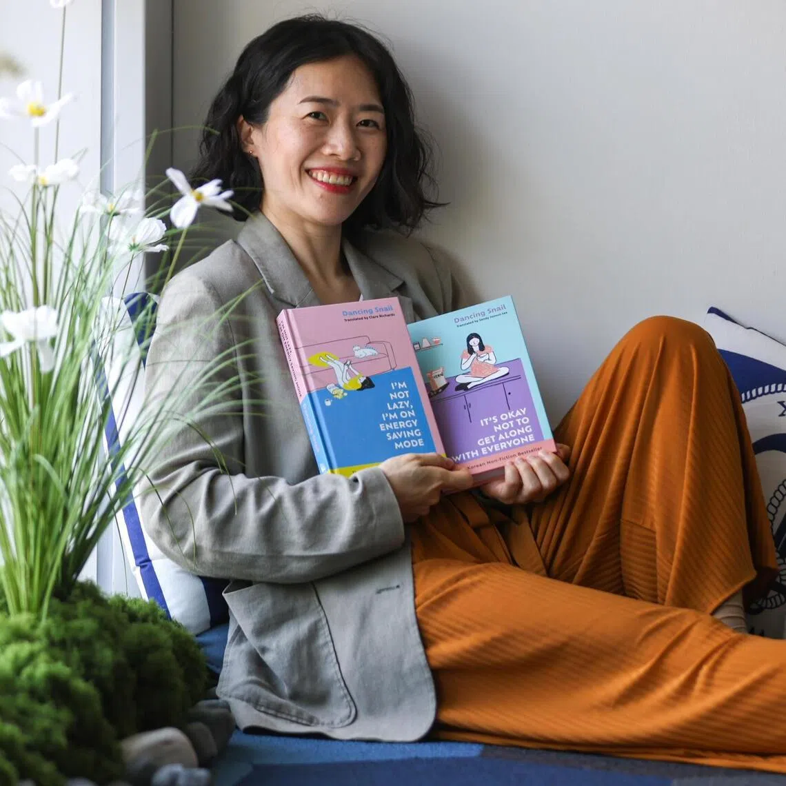ST20260409_202697900661/Jasel Poh/shsnail11

Bestselling Korean author illustrator Dancing Snail with her illustrated non-fiction books, It’s Okay Not To Get Along With Everyone and I’m Not Lazy, I’m On Energy Saving Mode, at the Straits Times office on April 9, 2026.