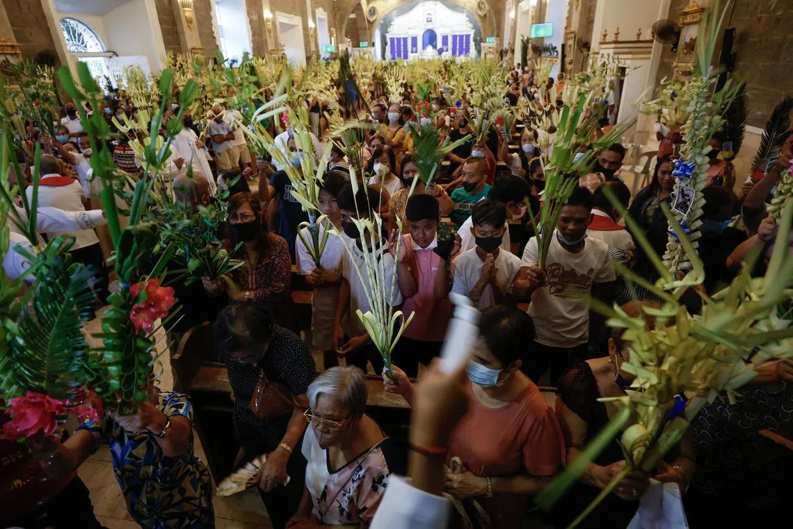 Catholic devotees raise palm fronds to receive a blessing to mark Palm Sunday inside a church in Bulacan province, north of Manila, Philippines.