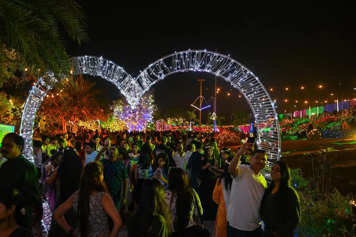 People gather at the sea promenade, lit up during sunset on New Year's Eve in Mumbai on Dec 31, 2022. 