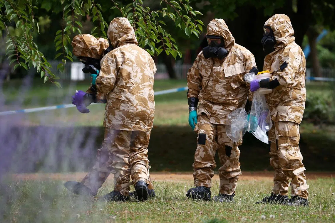 FILE PHOTO: People in military hazardous material protective suits collect an item and photograph its location in Queen Elizabeth Gardens in Salisbury, Britain, July 19, 2018. REUTERS/Hannah McKay/File Photo