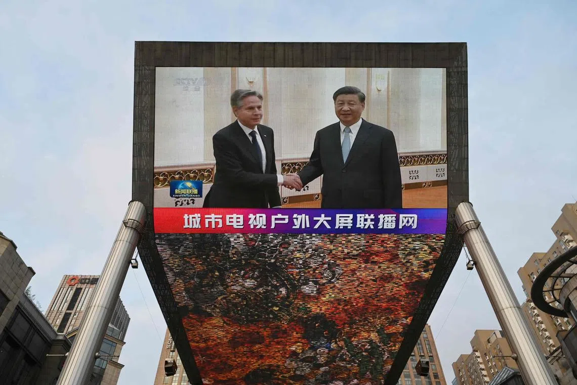 TOPSHOT - A China Central Television news broadcast shows footage of US Secretary of State Antony Blinken (L) meeting with China's President Xi Jinping, on a giant screen outside a shopping mall in Beijing on June 19, 2023. (Photo by GREG BAKER / AFP)